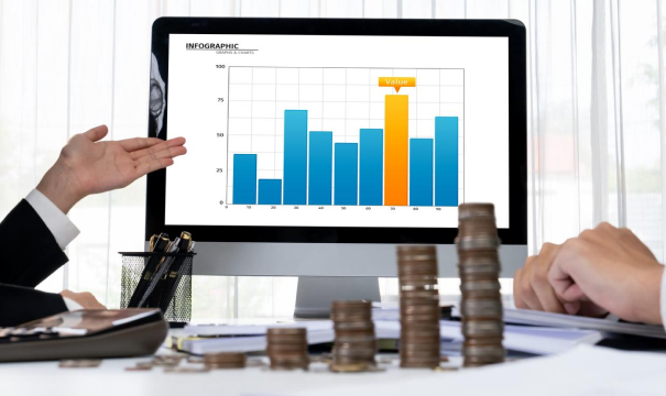 Two people in business attire examining a computer screen displaying a bar graph labeled 