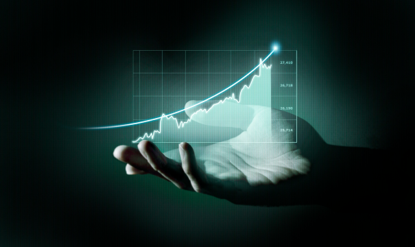 A hand is extended with a glowing holographic graph displaying a sharp upward trend against a dark background. The graph represents data progress or financial growth, highlighting increasing values as it ascends from left to right.