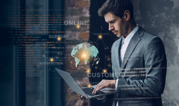 A man in a suit stands typing on a laptop. The background consists of HTML code, and augmented reality graphics depict a globe, along with words like 