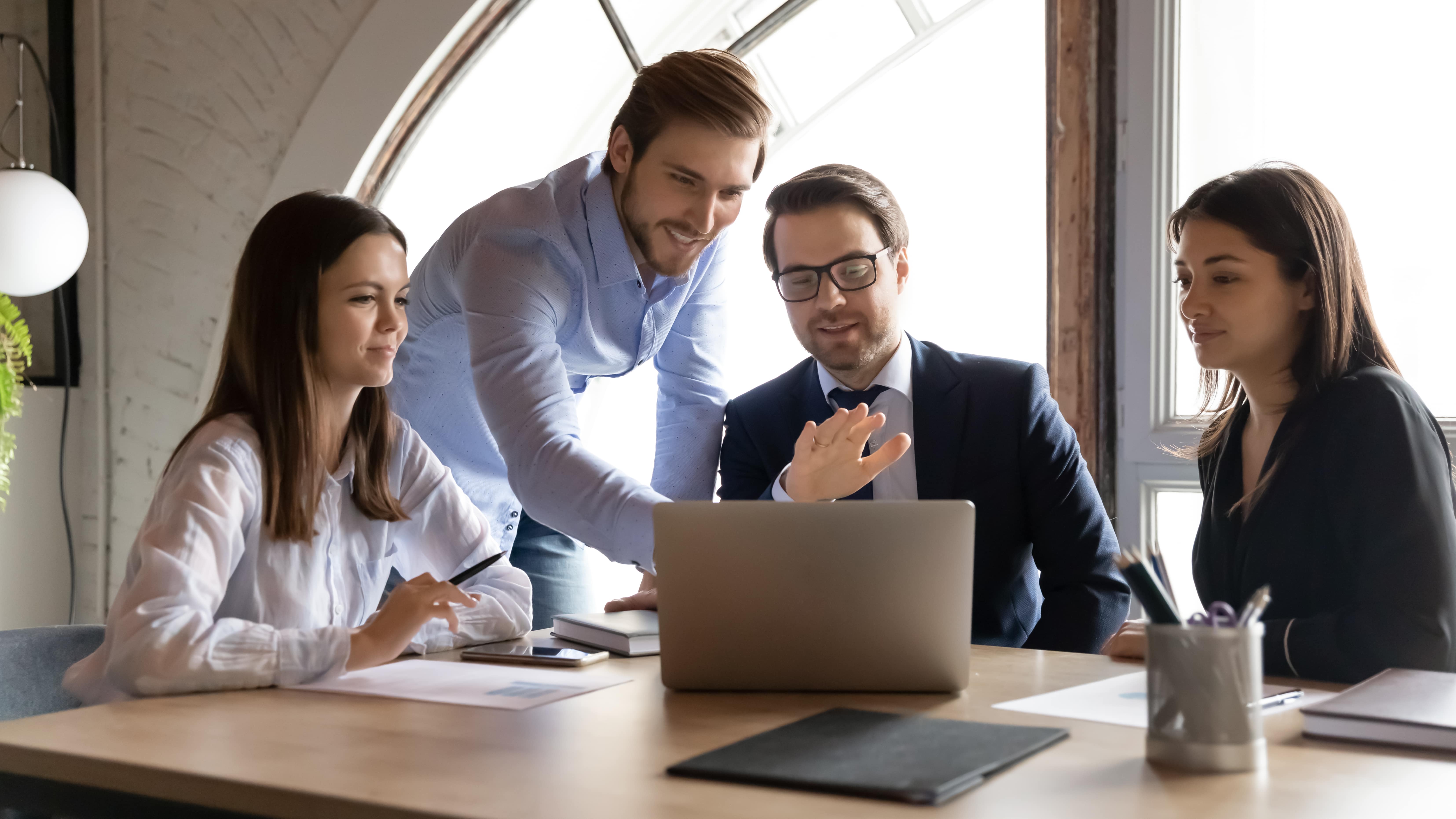 Smiling, diverse team working with a mentor to explore custom application development and workflow automation using modern digital tools.
